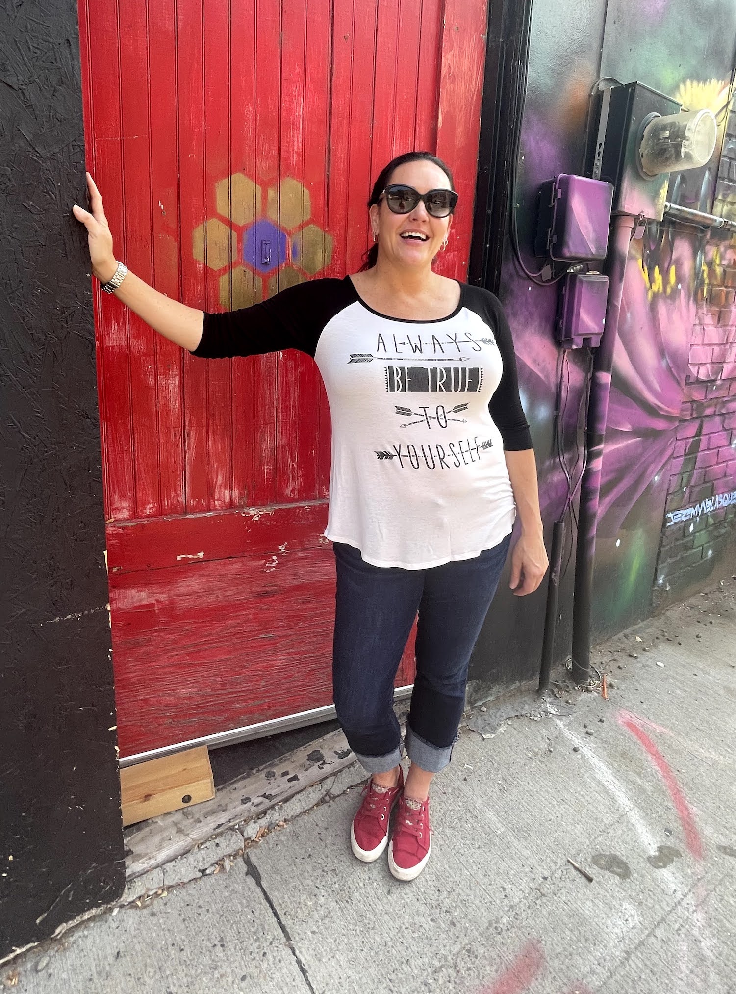Myofunctional Therapy Training Academy Carmen Woodland stands in front of a bright red door with a shirt that says always be true to yourself.